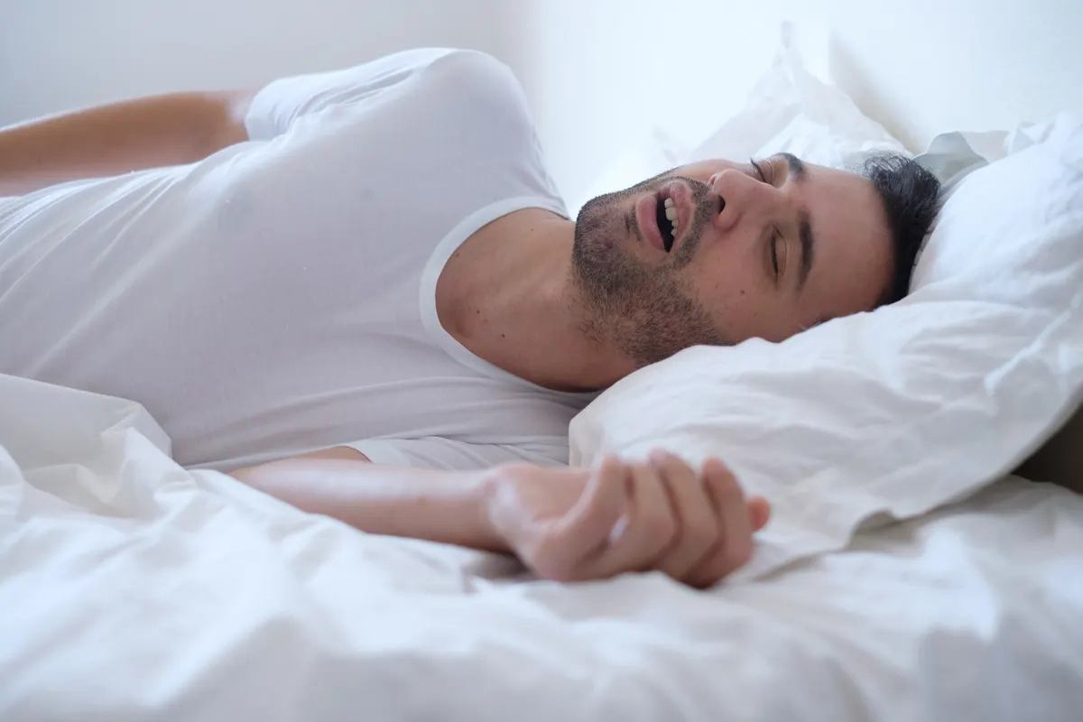 A couple in bed, one partner kept awake by the other&rsquo;s snoring
